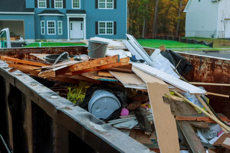 Household and renovation debris in a dumpster outside a home.