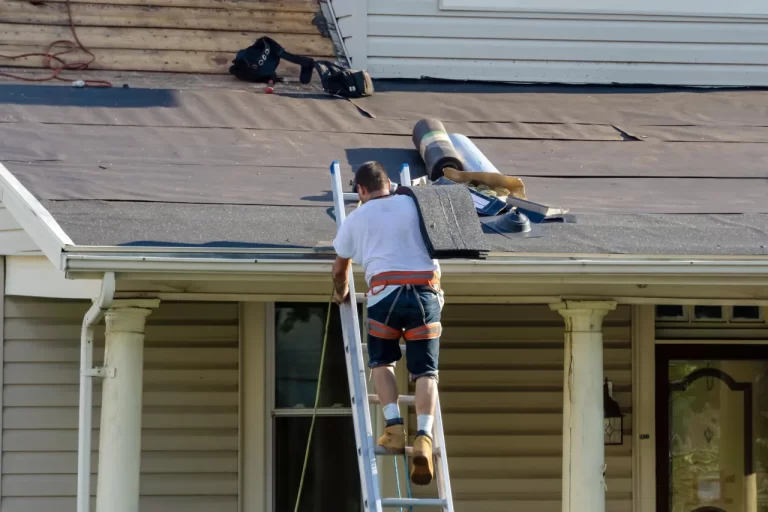 Roofing contractor carrying shingles up a ladder.