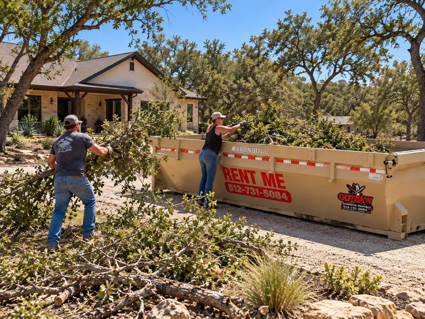 Homeowners loading cut tree limbs and brush into an Outlaw Dumpster Rentals roll-off dumpster during a residential land clearing and yard waste cleanup project.